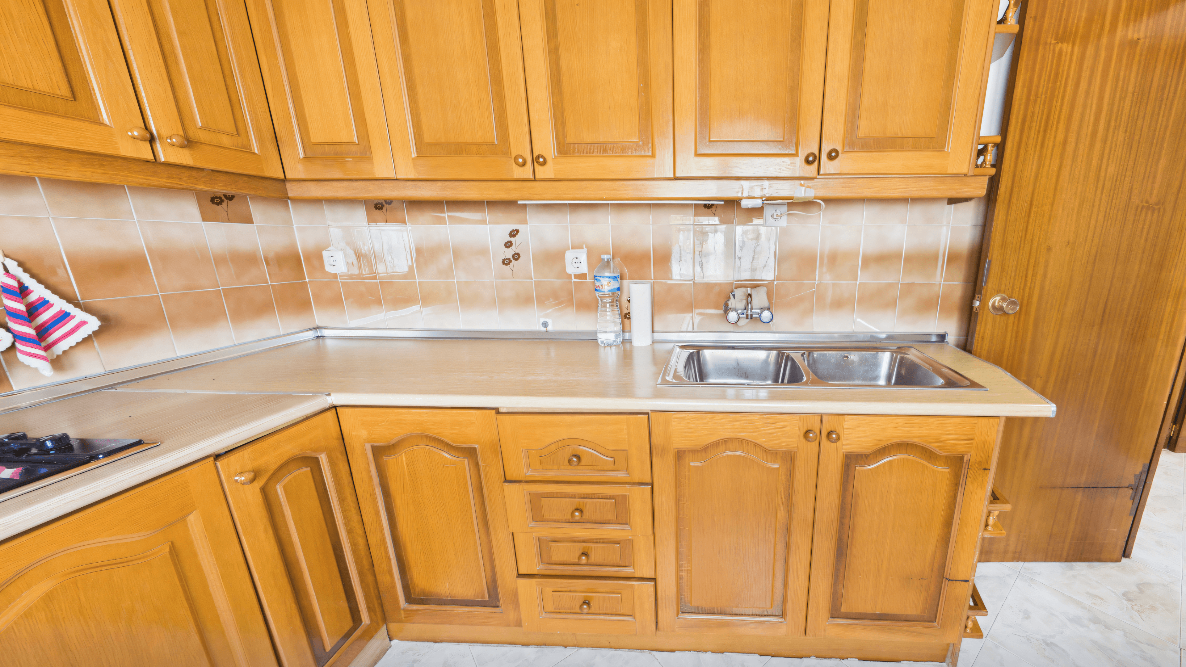 Before: old oak kitchen with beige tile backsplash and stainless-steel sink