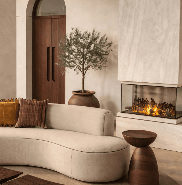 Curved sofa with fireplace and olive tree in a warm walnut-toned interior