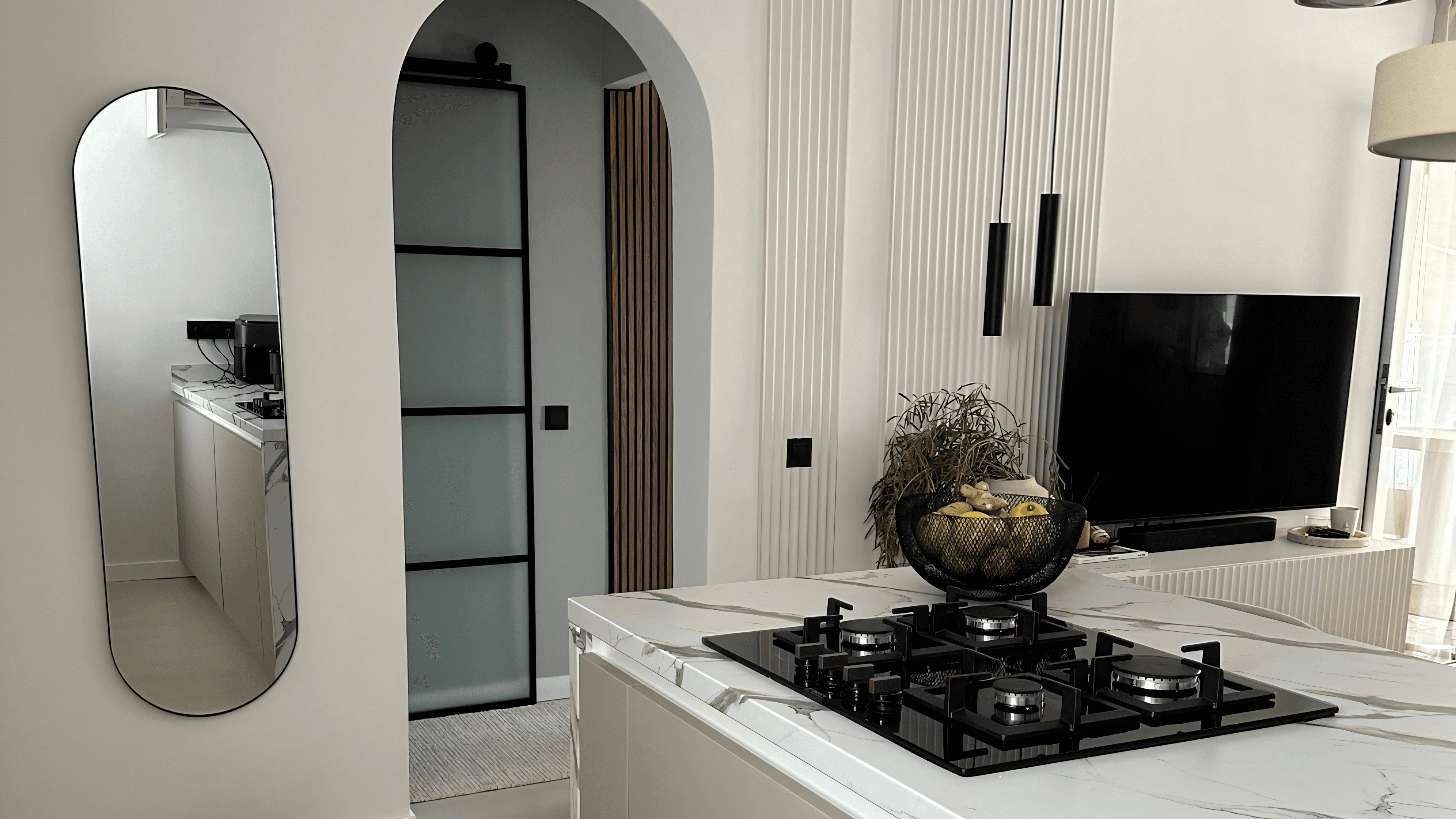 Kitchen island with gas hob, oval mirror and arched loft door to the hallway