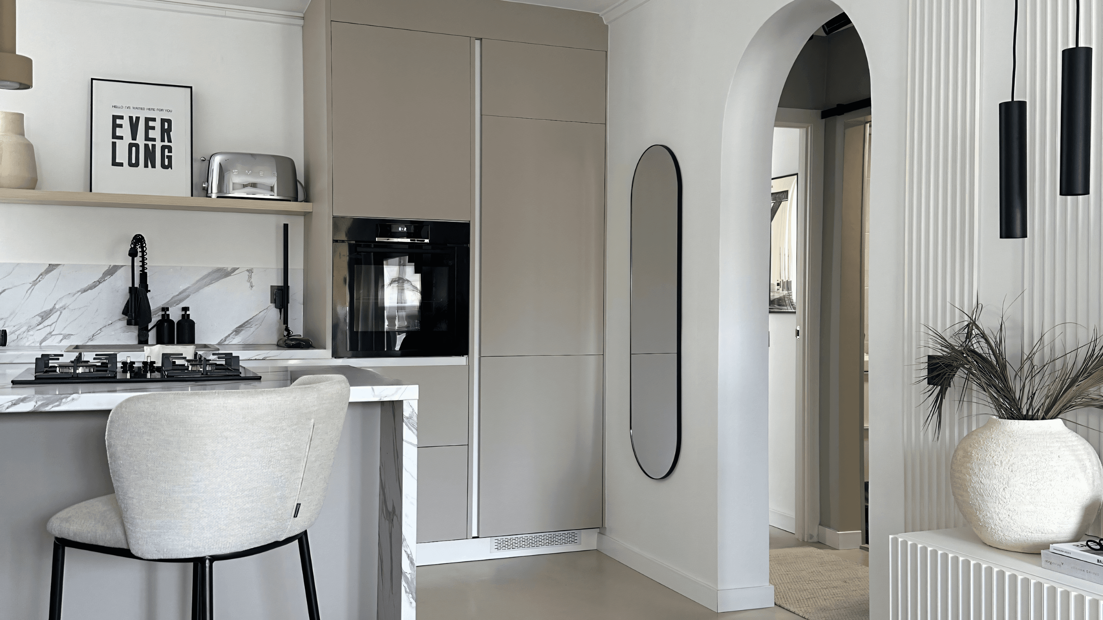Renovated kitchen with white marble, tall cabinets, arched doorway and bouclé bar stool, Torrevieja